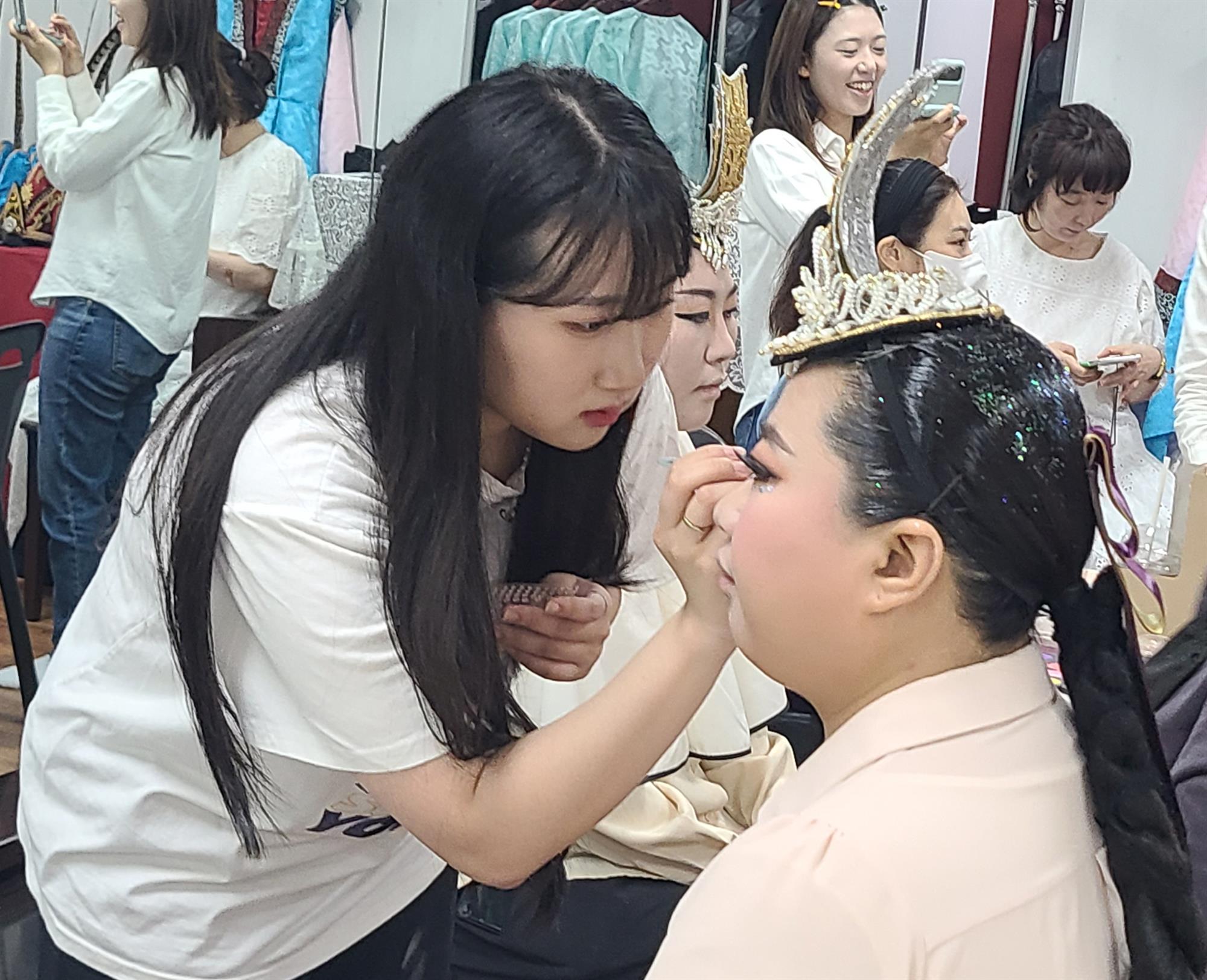 안산대학교 뷰티아트과 김지우 학생이 퍼레이드 참가자에게 분장을 하고 있다.